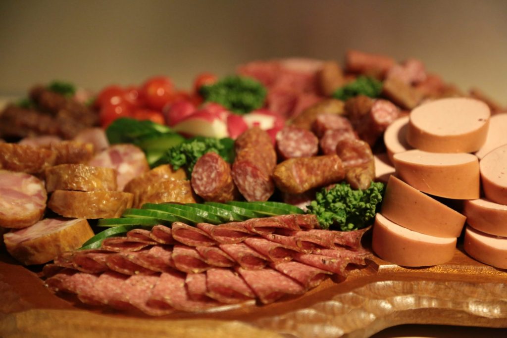 Geschnittenes Fleisch mit grünem Gemüse auf einem braunen runden Holzteller